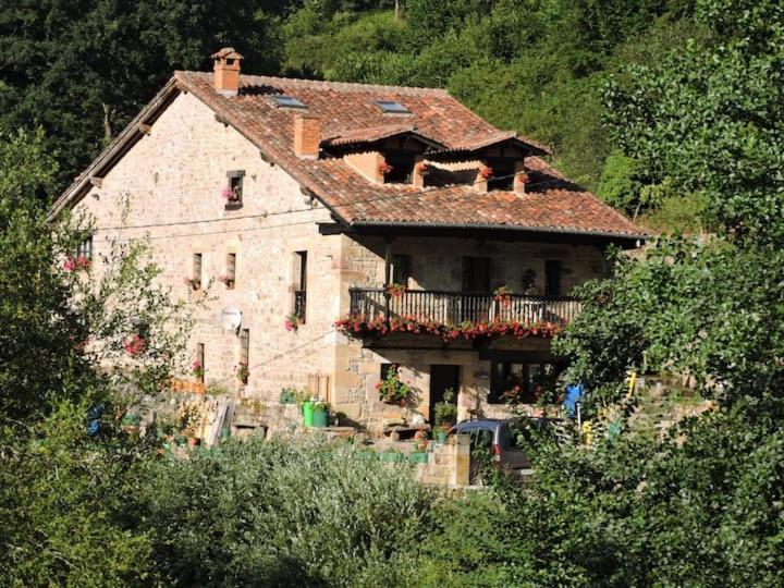 a large house with a balcony on a mountain at Casa rural La Bárcena Saja in Saja