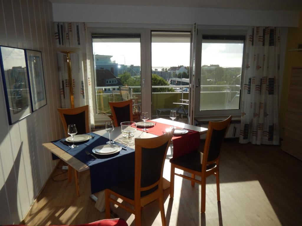 d'une salle à manger avec une table, des chaises et une fenêtre. dans l'établissement Ferienwohnung AMBIENTE, à Bremerhaven