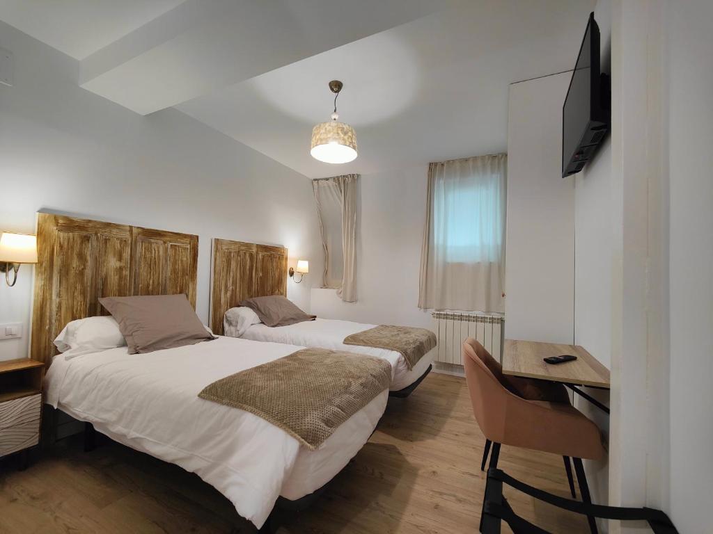 a bedroom with two beds and a desk and a television at Apartamentos Santander 2 in Santander