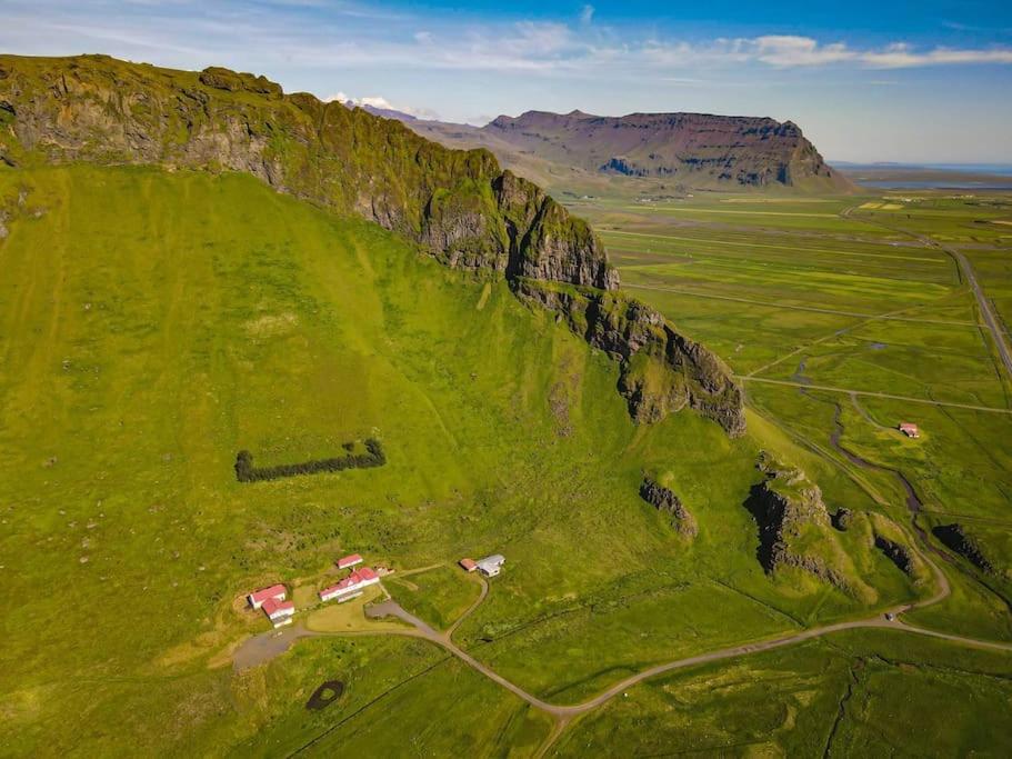 an aerial view of a green field with a mountain at Beautiful house with an outstanding view in Hvolsvöllur
