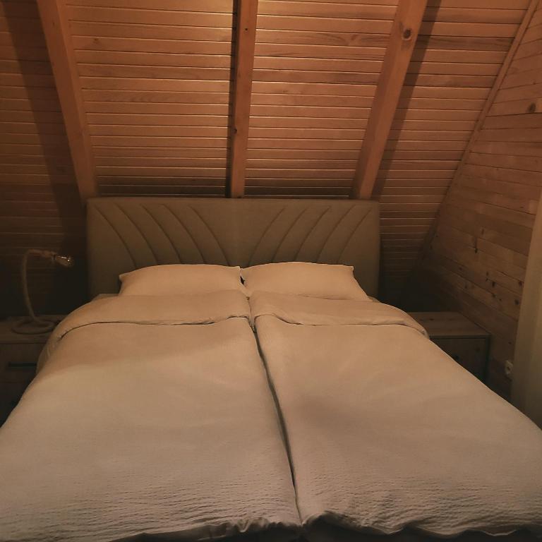 een bed met witte lakens en kussens in een kamer bij Luxury chalets Jasen in Han Pijesak