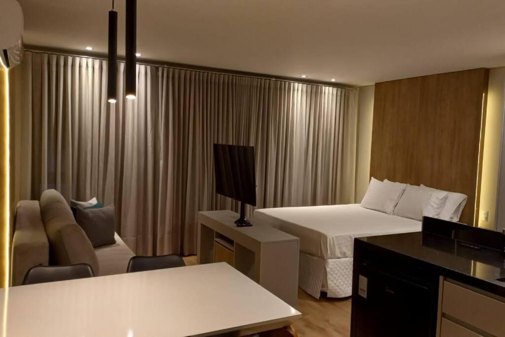 a hotel room with a bedroom with a bed and a tv at Apartamento - Batel/Água Verde - Shopping Curitiba in Curitiba