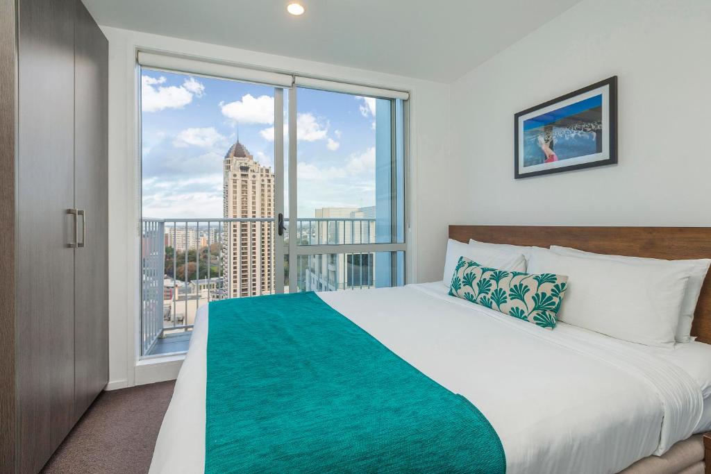 a bedroom with a bed and a large window at Barclay Suites in Auckland