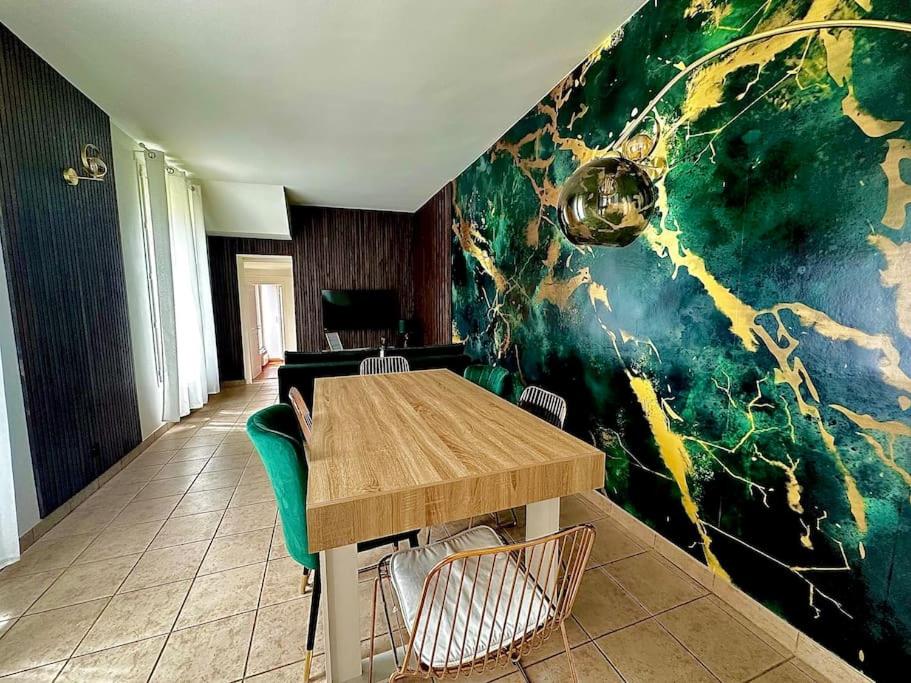 una sala da pranzo con tavolo e parete colorata di GREENWOOD CHATOU - 1 chambre - 4 Pers - Wifi a Chatou