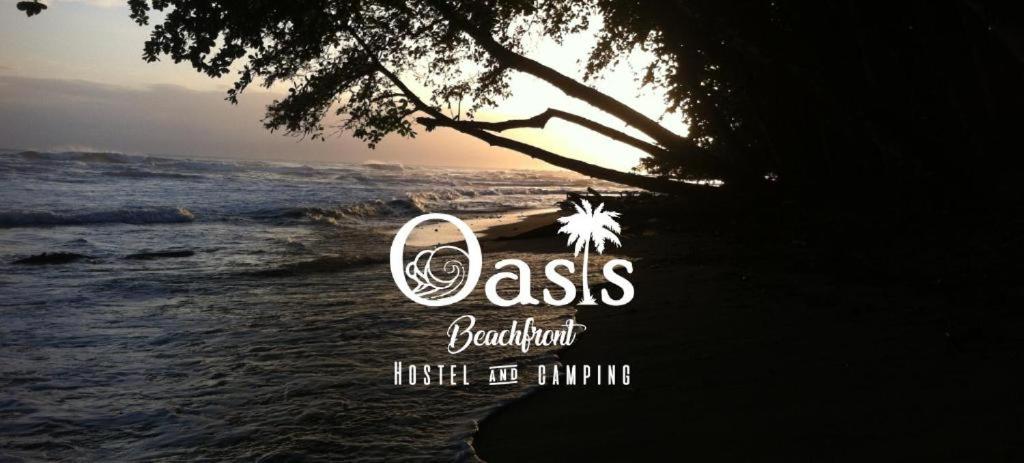 logotipo de un complejo de playa con el océano en Oasis Beachfront Hostel, en Puerto Limón