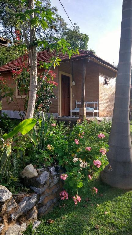 a house with a tree and flowers in front of it at Sitio Pousada Morada do Sol in Cunha