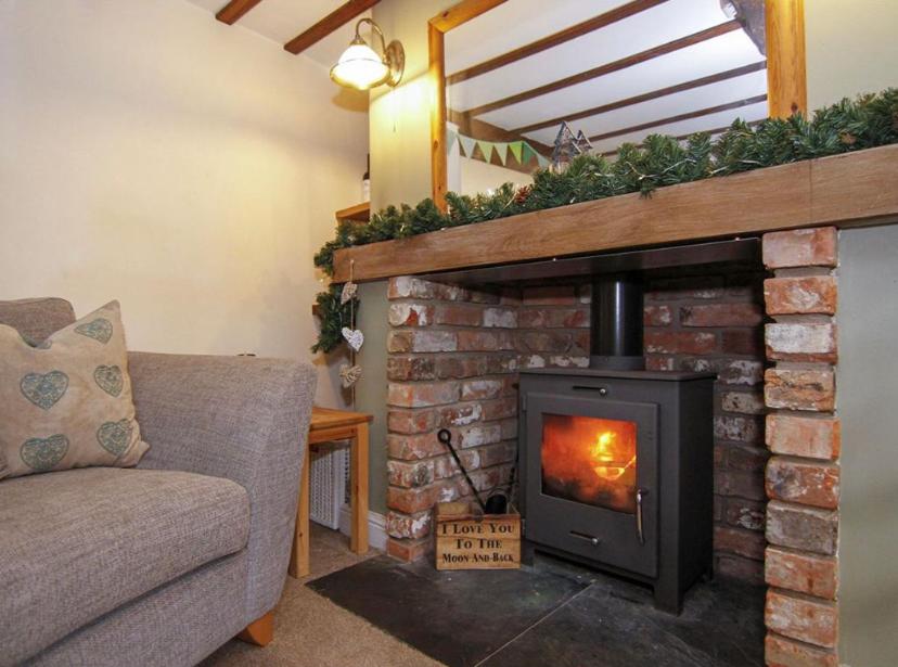 a living room with a brick fireplace with a stove at Daisy Cottage in Warminster
