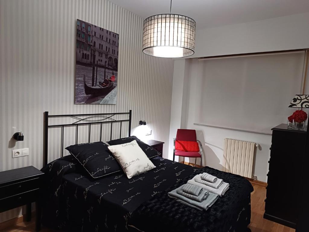 ein Schlafzimmer mit einem schwarzen Bett und einem roten Stuhl in der Unterkunft María Belkis in Ourense