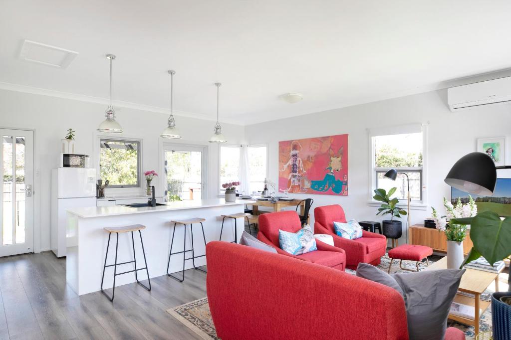 a living room with red chairs and a kitchen at The Alfred, Mittagong in Mittagong