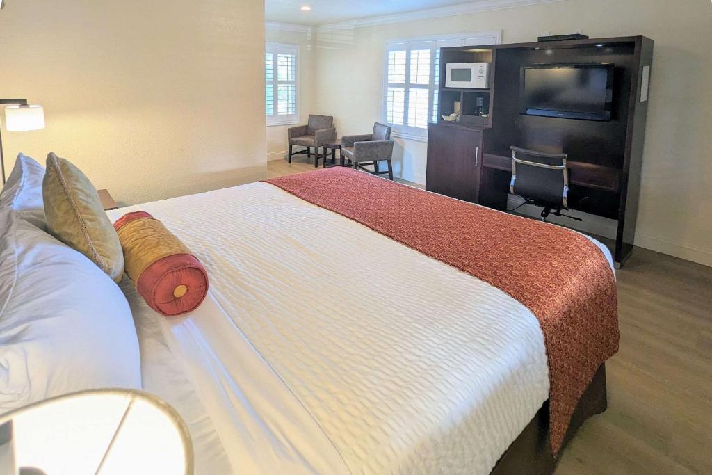 a hotel room with a large bed and a flat screen tv at Clarion Collection Wilkie's Inn Pacific Grove - Monterey in Pacific Grove
