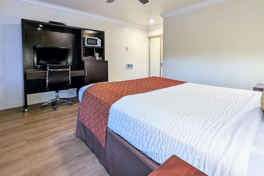 a bedroom with a bed and a desk and a television at Clarion Collection Wilkie's Inn Pacific Grove - Monterey in Pacific Grove