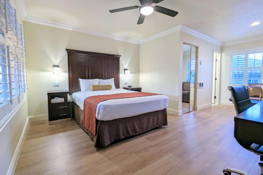 a hotel room with a bed and a ceiling fan at Clarion Collection Wilkie's Inn Pacific Grove - Monterey in Pacific Grove