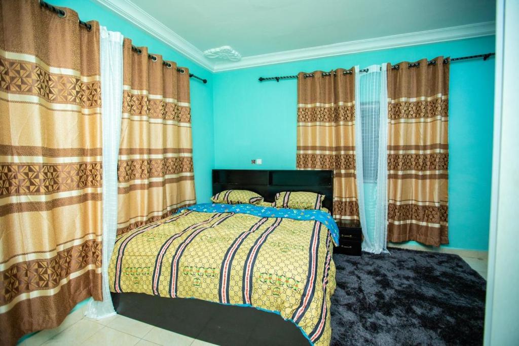 a bedroom with a bed with blue walls and curtains at Matata Homes Airbnb in Kasoa
