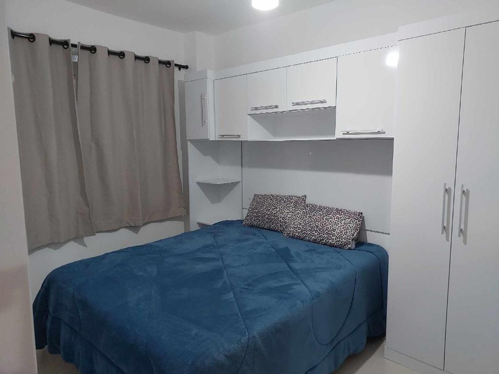 a bedroom with a blue bed and white cabinets at Apartamento belvedere do lago in Serra Negra