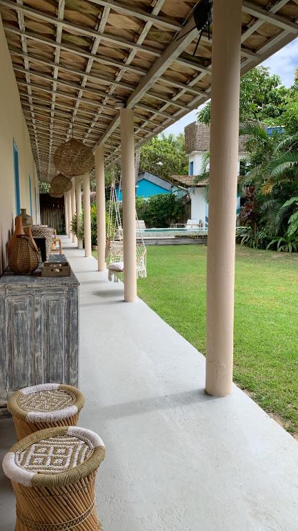 porche cubierto con sillas de mimbre y mesa en Pousada Caraíva, en Caraíva