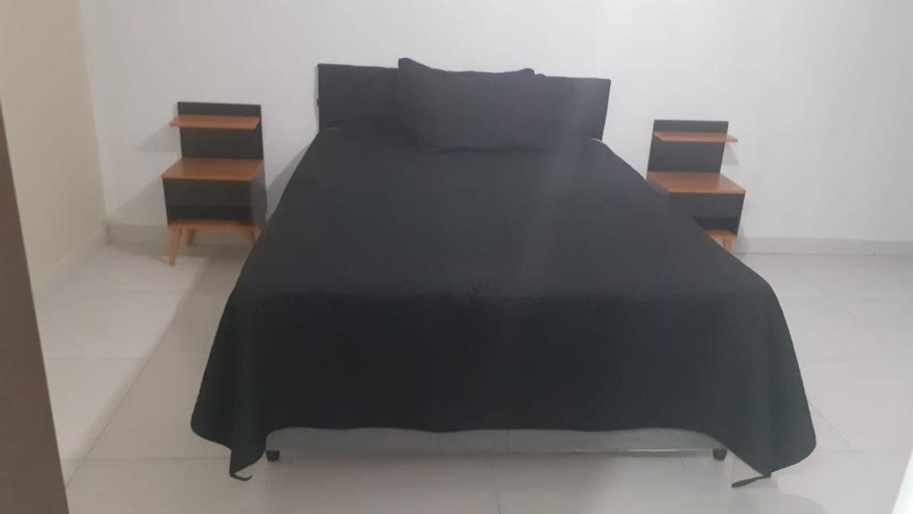 a bed with a black blanket and two night stands at Cantinho da tati in Itu