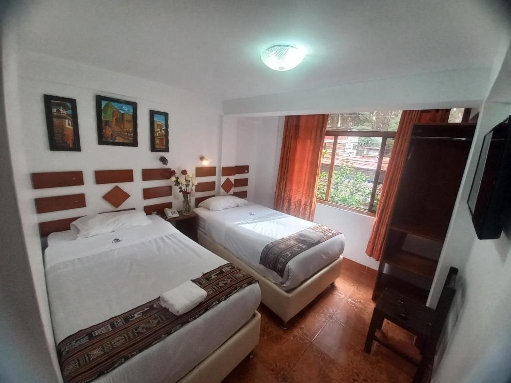 a bedroom with two beds and a window at PAQARIQ INN HOTEL in Machu Picchu