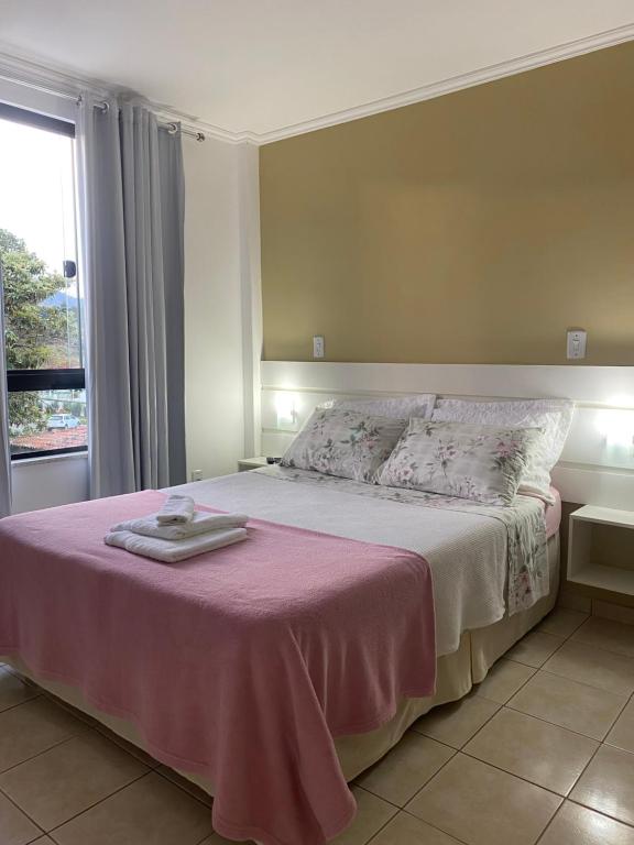 a bedroom with a large bed with a pink blanket at Pousada da Mariinha in São Lourenço