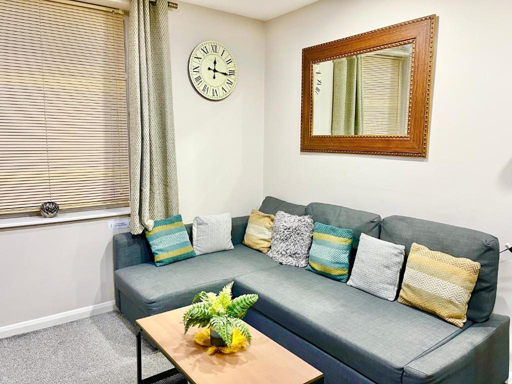 a living room with a blue couch and a clock at Ar-Rahman, 1 bed room and 1 Living room apartment in Kent