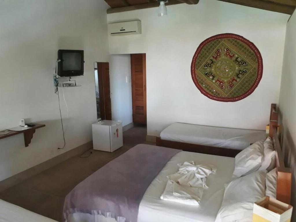 1 dormitorio con 2 camas y TV en la pared en POUSADA CANTINHO MÁGICO, en Maraú