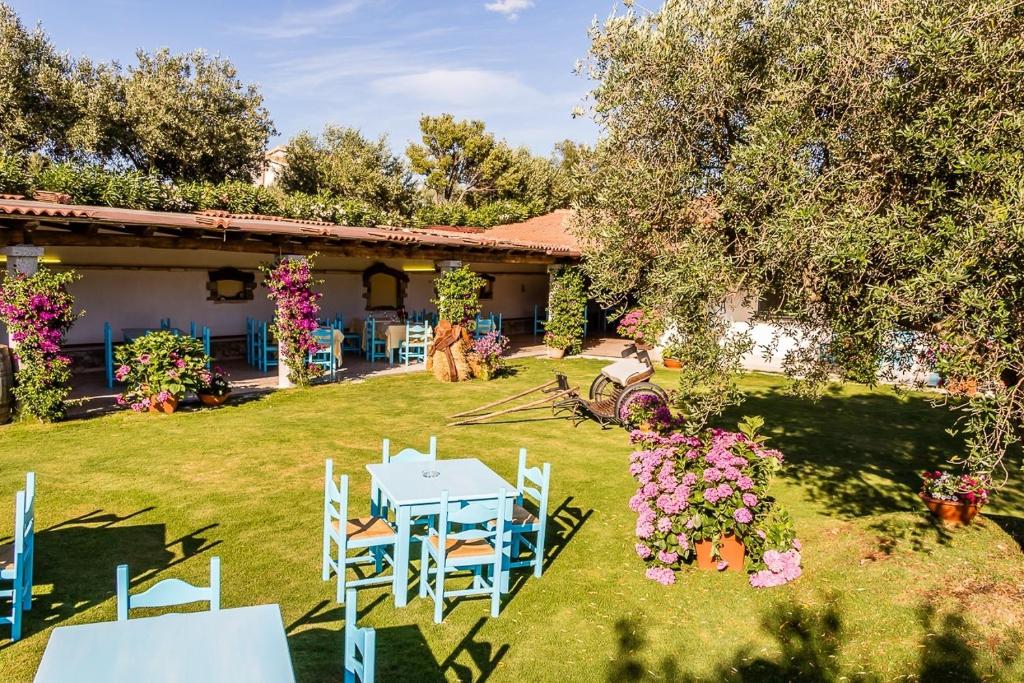 einen Garten mit einem Tisch, Stühlen und Blumen in der Unterkunft Piccolo Ranch in Pula