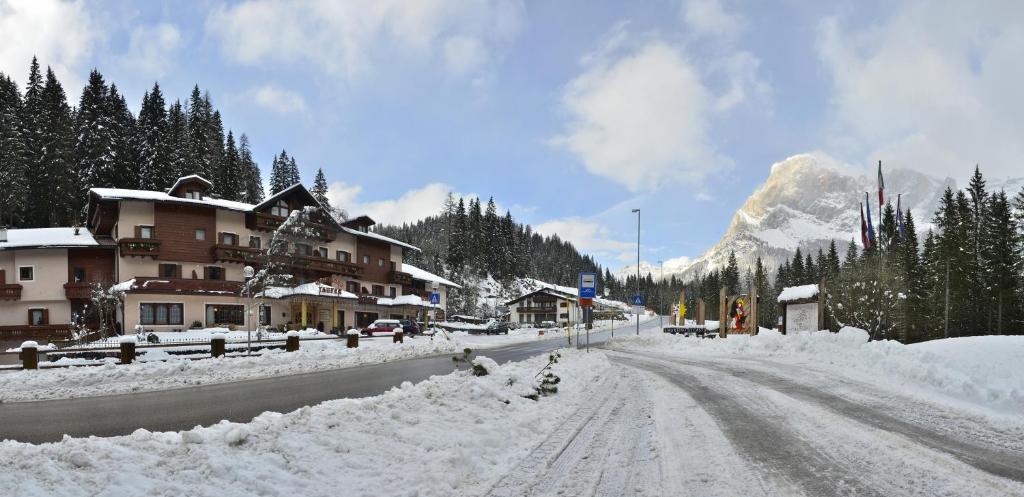 a snow covered street with a building and a mountain at Residence Taufer in San Martino di Castrozza