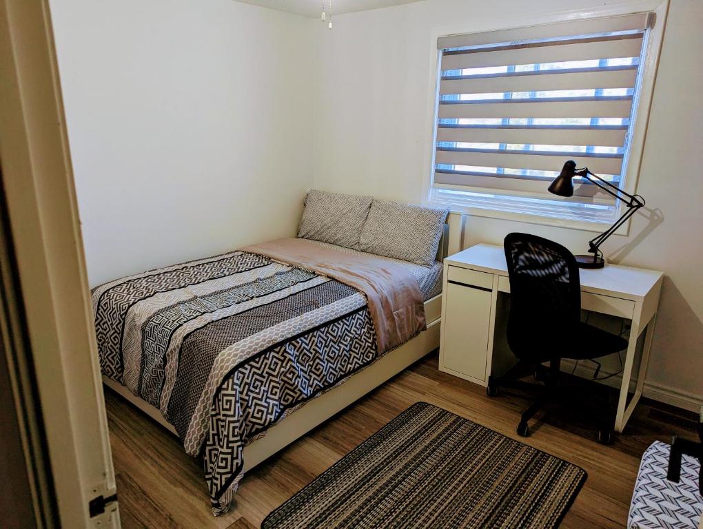 Schlafzimmer mit einem Bett, einem Schreibtisch und einem Stuhl in der Unterkunft Home of Pleasantness in Hamilton