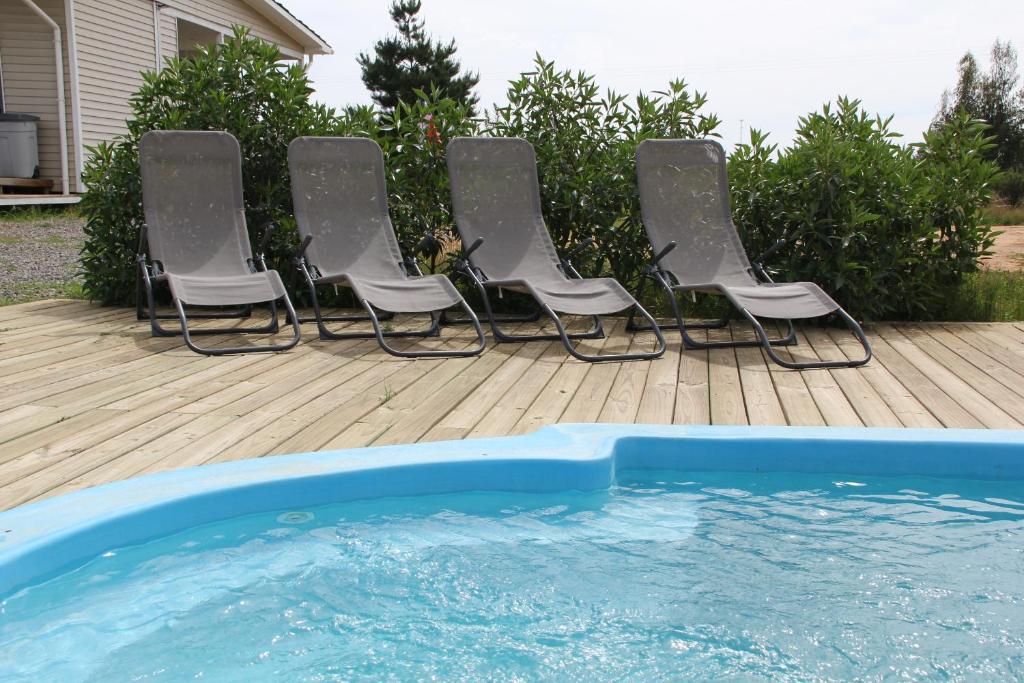 a group of chairs sitting next to a pool at Cabaña con fogon y tinaja en plena naturaleza! in Algarrobo