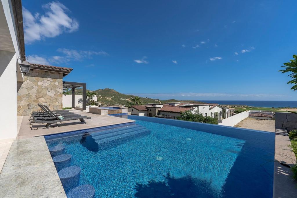 a blue swimming pool with a view of the ocean at Seaside Serenity A Luxurious Coronado Home in Cabo San Lucas