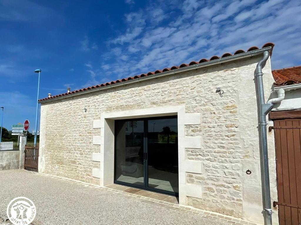 a white brick building with a large glass door at Maison confortable 6 pers. - 20km de La Faute sur Mer - 67km Puy du Fou - Terrasse et Proximité Routes - FR-1-426-534 in Les Magnils-Reigniers