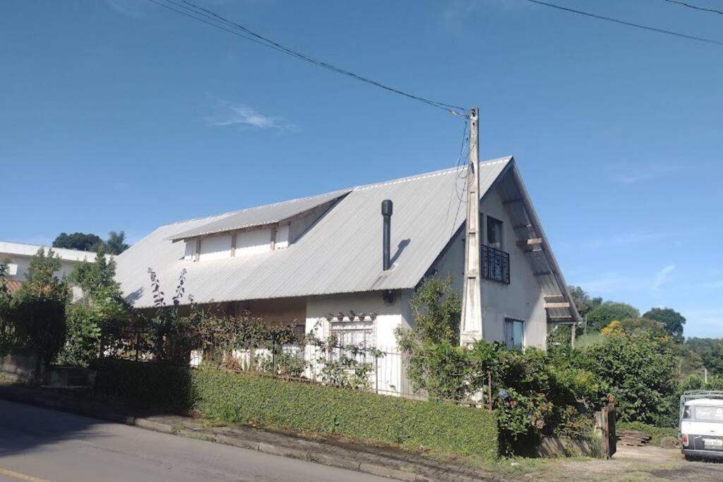 una casa bianca con un tetto d'argento su una strada di GartenHaus a São Bento do Sul
