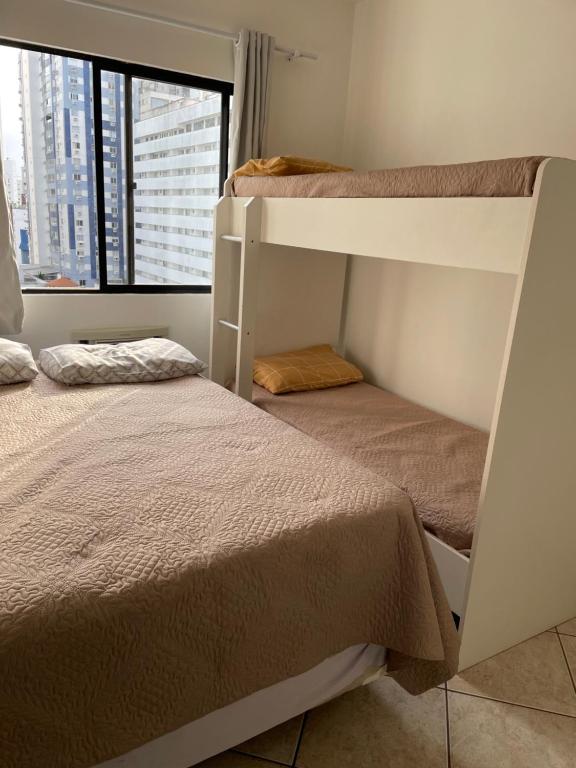 two bunk beds in a room with a window at Apartamento Dante Tomio in Balneário Camboriú