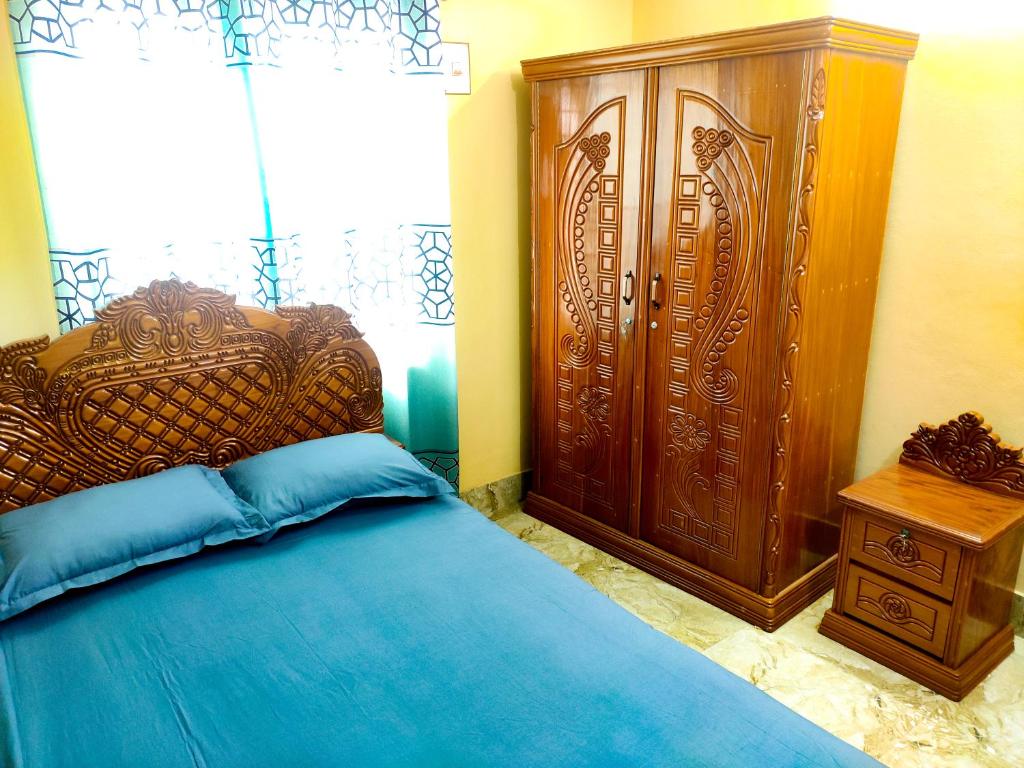 ein Schlafzimmer mit einem Bett und einem großen Holzschrank in der Unterkunft Asma-ul-husna apartment in Rajshahi