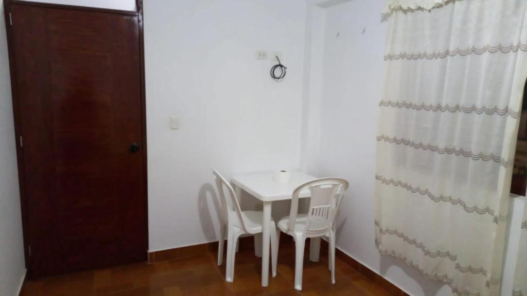 einen weißen Tisch und Stühle in einem Zimmer mit Tür in der Unterkunft Bella Guest House in Chachapoyas