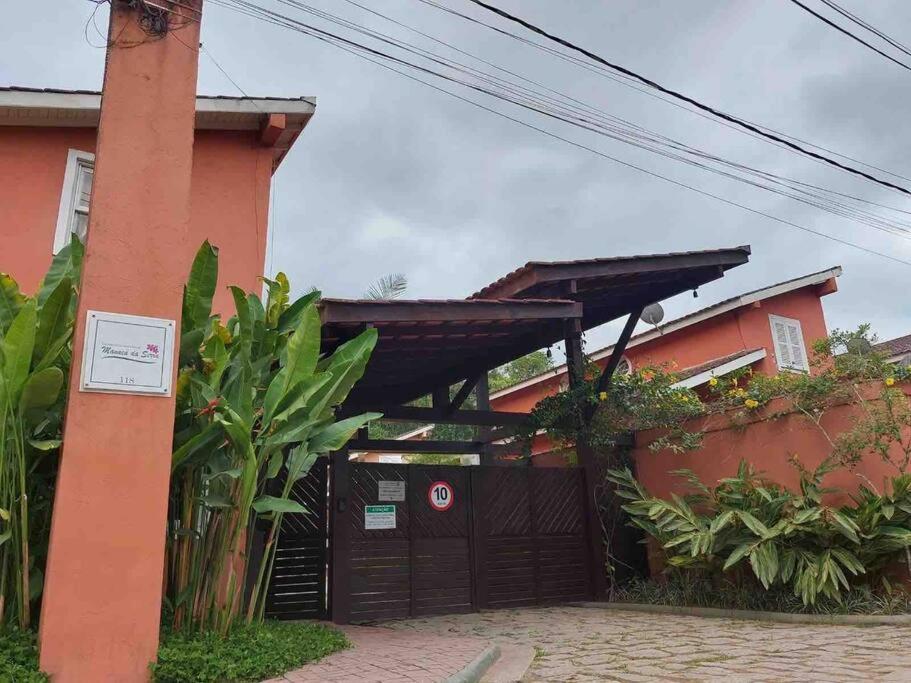 a red building with a black gate and a fence at Esplendor House - Little Cambury in São Sebastião