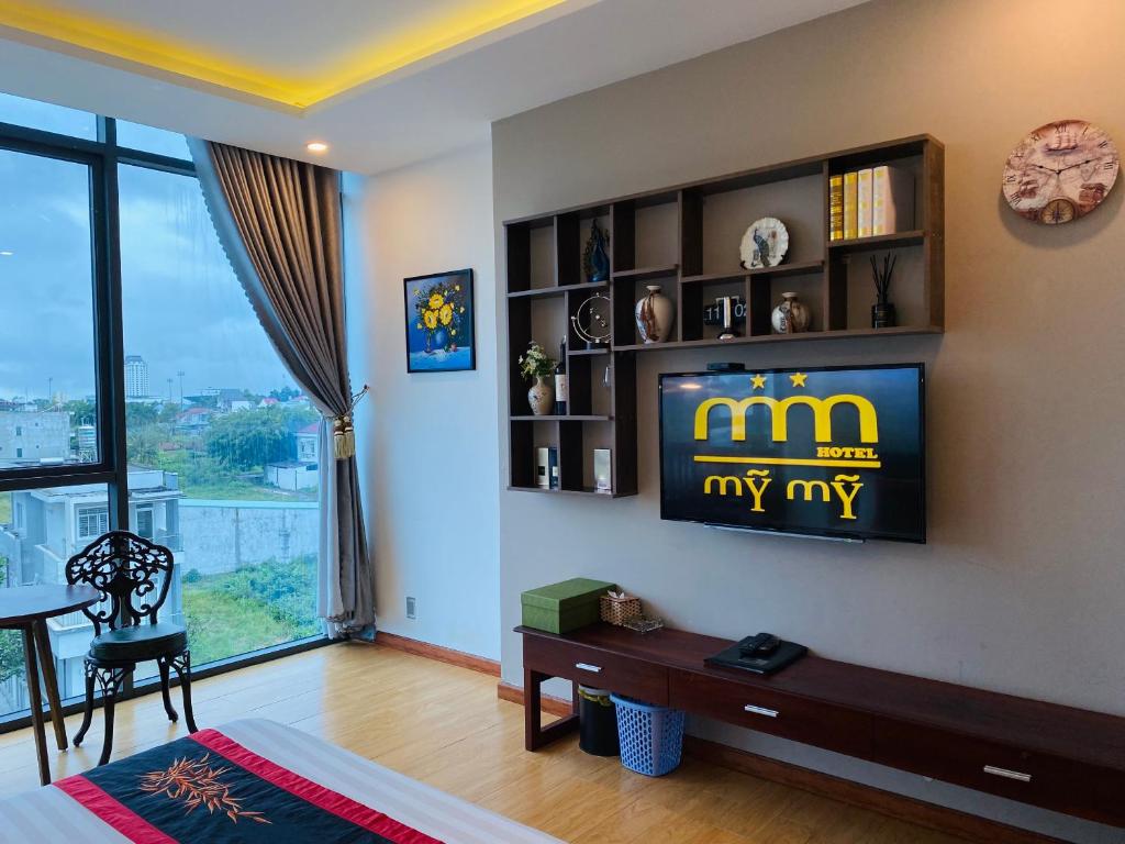 a living room with a television on a wall at Hotel Mỹ Mỹ in Tây Ninh