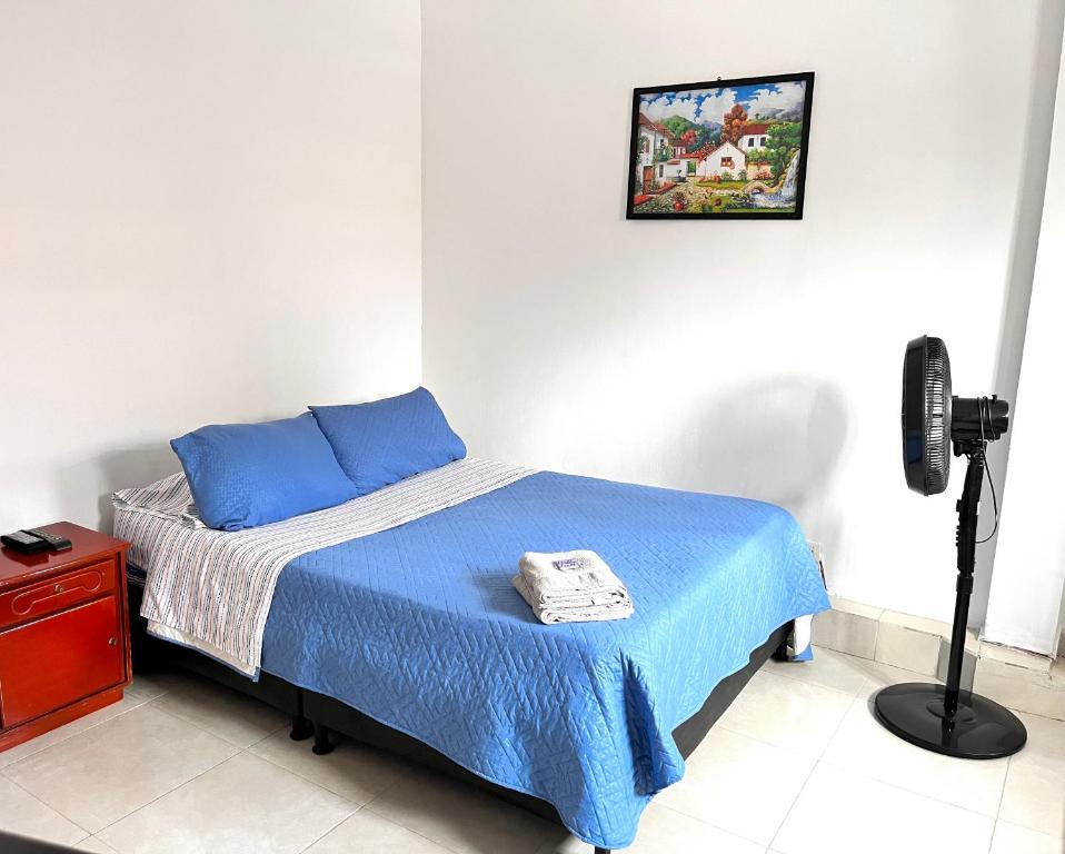 um quarto com uma cama com um cobertor azul em Apartaestudio Centro Pereira em Pereira