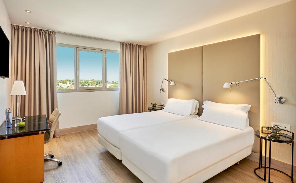 um quarto de hotel com uma cama branca e uma janela em NH Ciutat de Reus em Reus