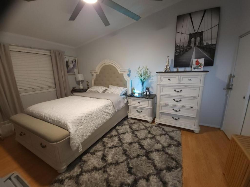 a bedroom with a white bed and a dresser at Little Paris Eiffel Tower Suite in Owings Mills