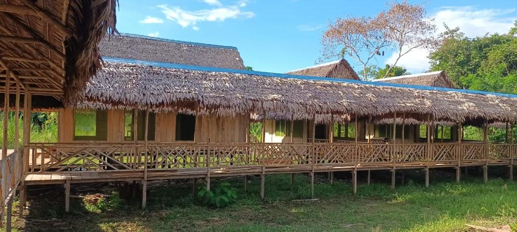 budynek z dachem krytym strzechą i werandą w obiekcie Canoa Inn Natural Lodge w mieście Iquitos