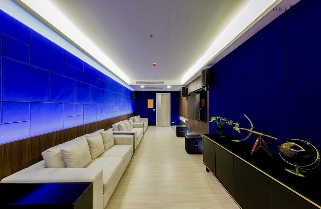 a waiting room with white couches and a blue wall at Central world Rama9/One9five公寓/Jadd夜市 in Bangkok