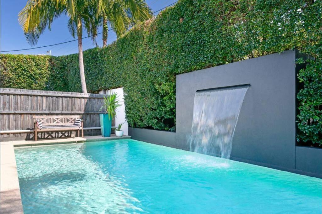 a swimming pool with a waterfall in a backyard at Casa de Palmas Noosa in Noosaville