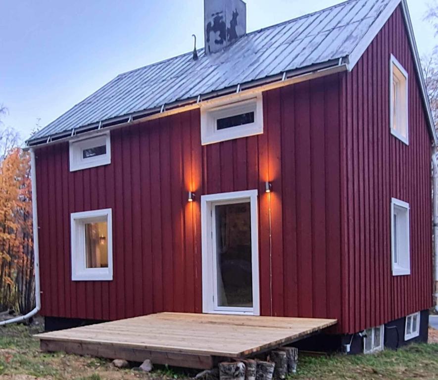 eine rote Scheune mit einer Holzterrasse davor in der Unterkunft Liebevoll renoviertes Ferienhaus im schwedischen Lappland 