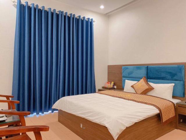 1 dormitorio con 1 cama grande y cortinas azules en Hương Quê - 7 Ngõ Ga, Phú Lương, Hà Đông - by Bay Hostel, en Hà Ðông