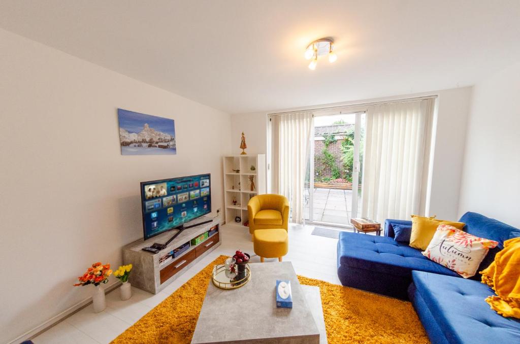 a living room with a blue couch and a tv at Spacious House near Kings Cross in London