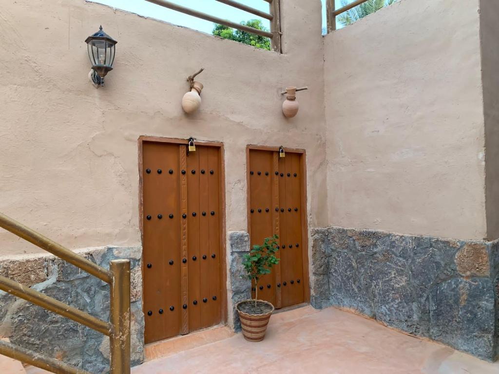 two wooden doors in the side of a building at بيت نُزل السلام Bait Salam inn in Al Ḩamrāʼ