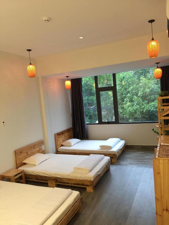 three beds in a room with a large window at Homestay KV in Can Tho