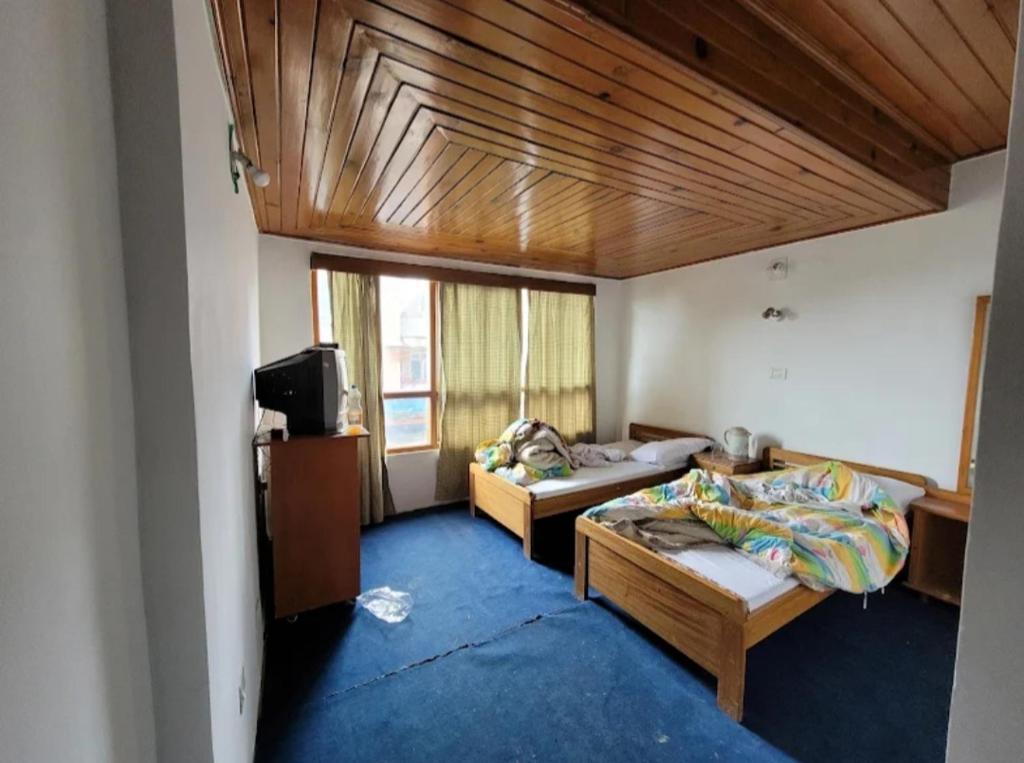 Cette chambre comprend 2 lits et une télévision. dans l'établissement Hotel Tawang Inn, à Tawang