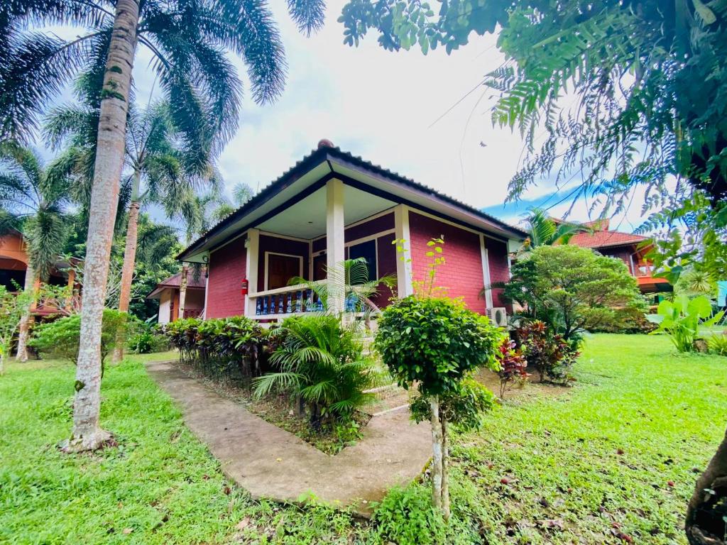 a red house with palm trees in front of it at Khao Sok Nung House in Khao Sok