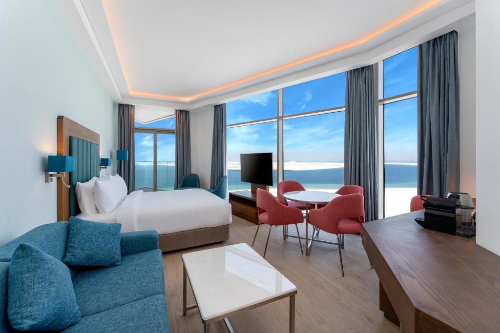 Park Regis by Prince Dubai Islands في دبي: غرفة فندق بسرير كنج وغرفة معيشة